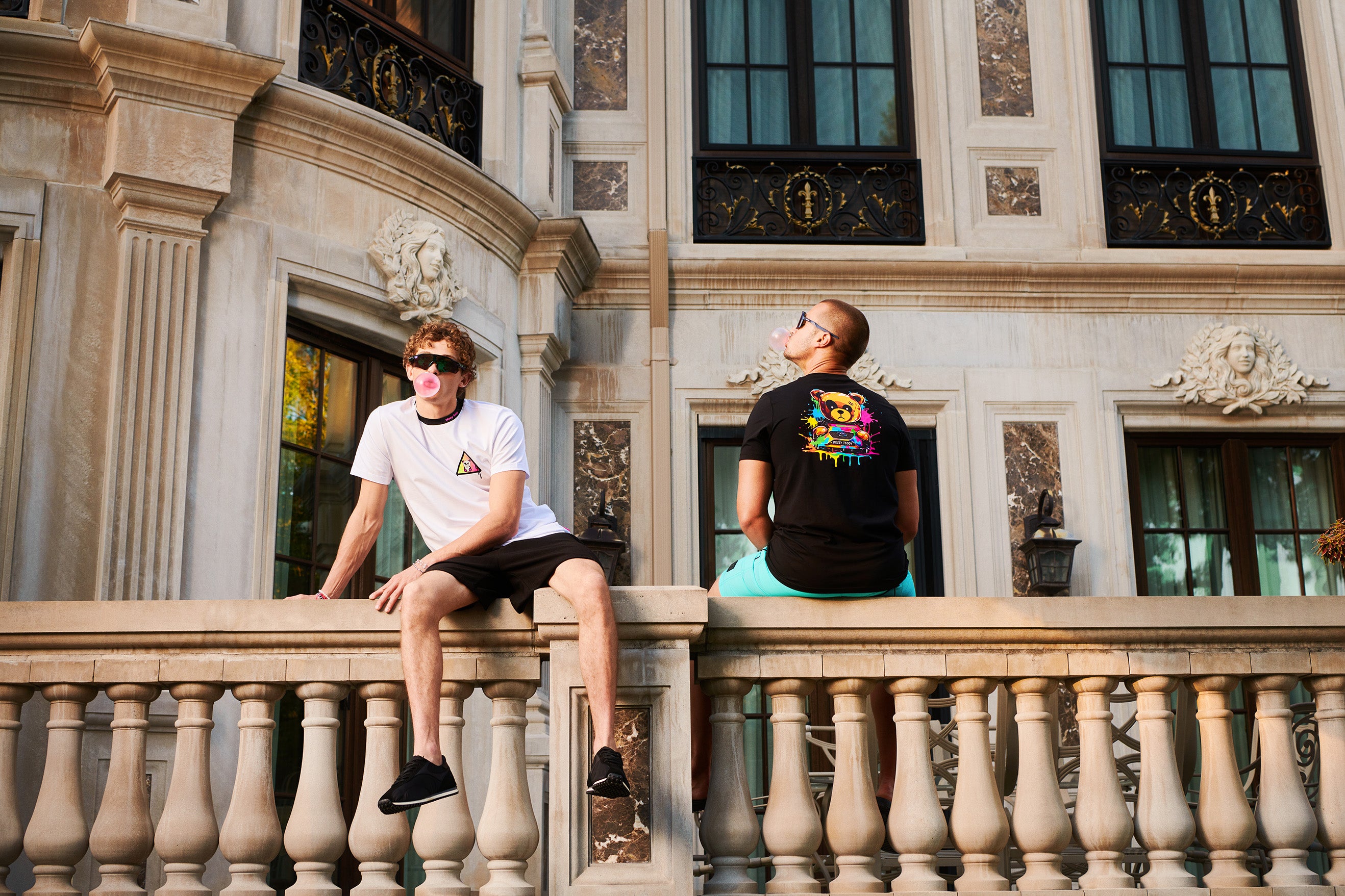 Two people sitting on a stone balcony of an ornate building.
